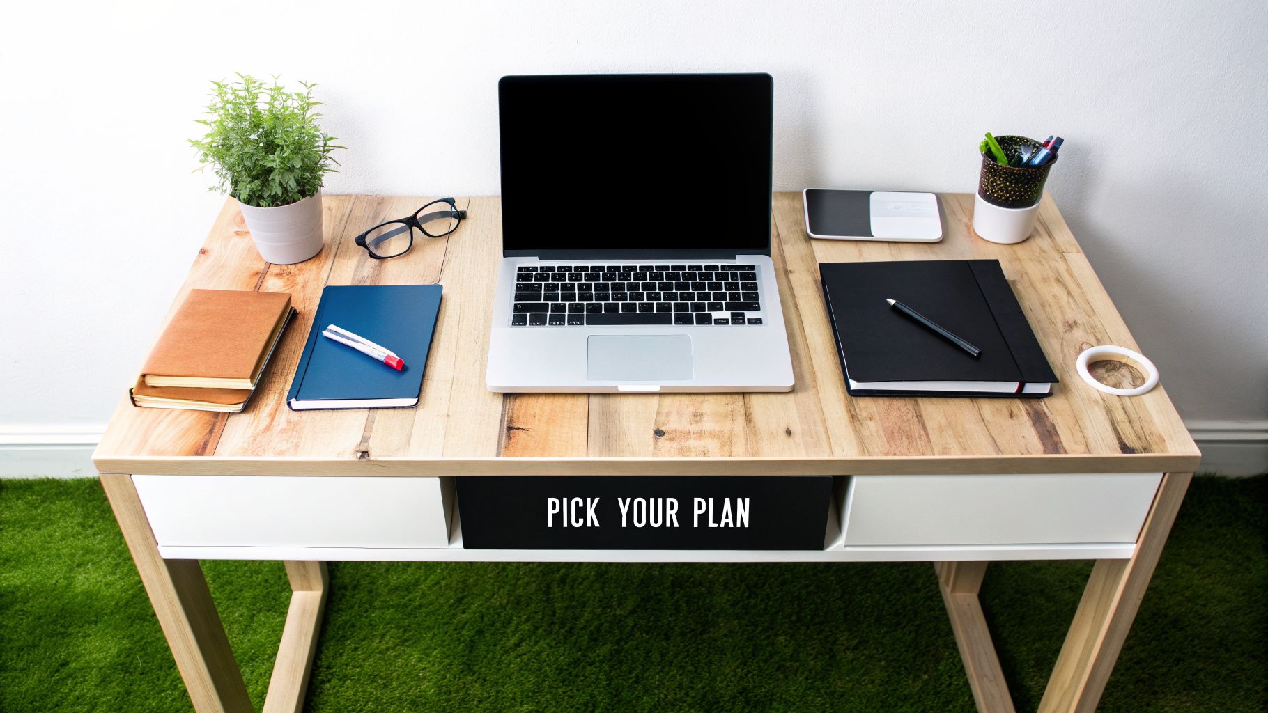 A modern, organized flatlay of a wooden desk with a laptop, notebooks, glasses, and a plant.
