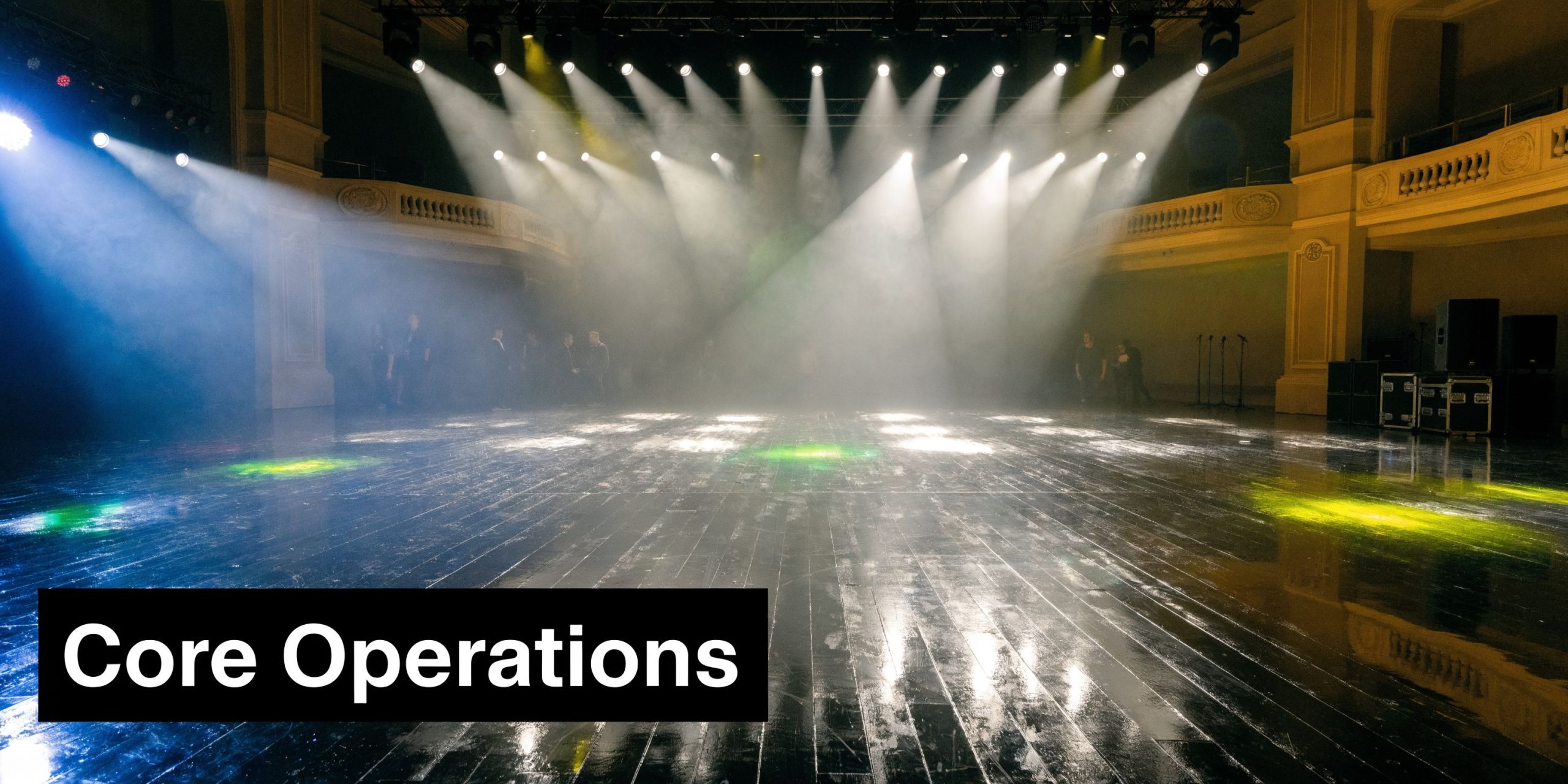 A large, empty stage with professional lighting, stage fog, and a polished floor in a concert venue.