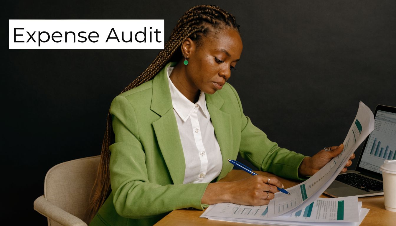 A professional woman in a green blazer reviewing financial expense audit documents while working at her desk.